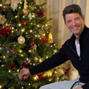 Ο Σάκης Ρουβάς ποζάρει δίπλα στο χριστουγεννιάτικο δέντρο στο σπίτι του